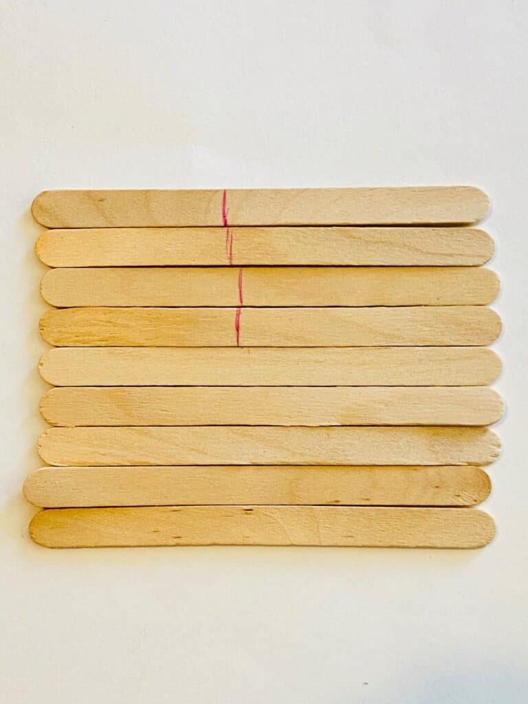 Use a pen to section off the portion of the popsicle sticks that will be painted blue