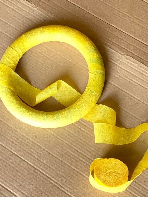 Continue all the way around, until you have covered the entire foam wreath with 2 layers of yellow crepe paper streamers