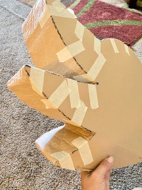 Begin to shape the long, bendy cardboard piece around the outline of the Sonic, securing with masking tape every 1-2 inches.