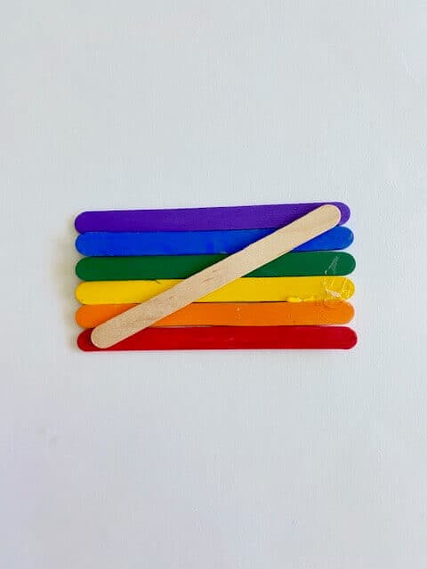Line them up in the order Red, Orange, Yellow, Green, Blue, Purple and glue a plain popsicle diagonally across the back.