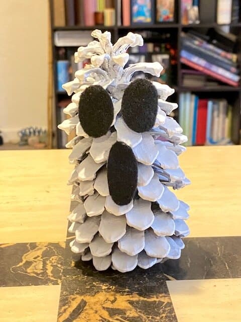 Glue the ghostly eyes and mouth onto the painted white pine cone