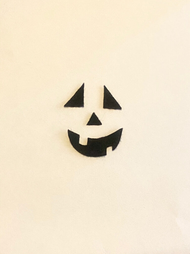 Cut the Jack-O-Lantern face out of black felt. 2 triangle eyes, triangle nose and missing teeth smile.