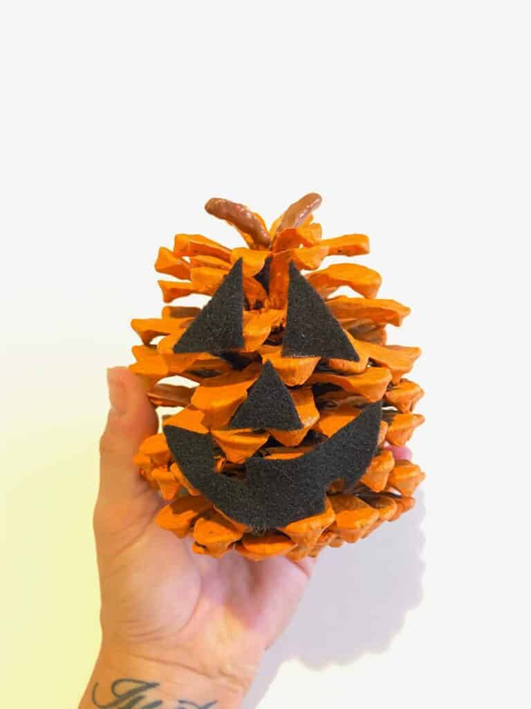 Glue the jack-o-lantern face to onto the front of the orange pine cone