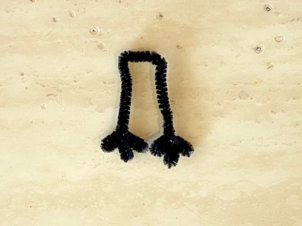 Make the black pipe cleaner into feet.