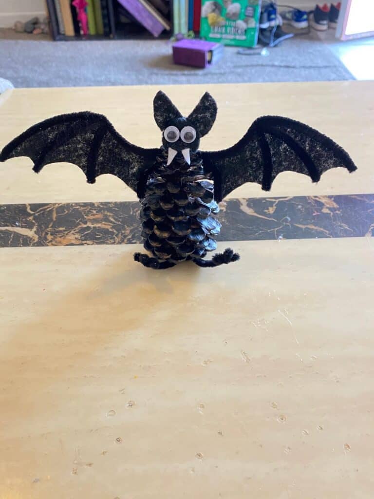 Glue the bats wings to each side of the pine cone body.
