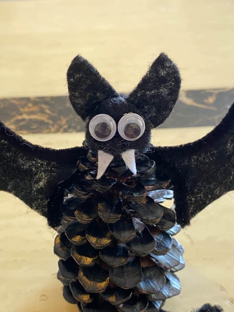 glue the googly eyes, fangs, and the ears in place on the bats head