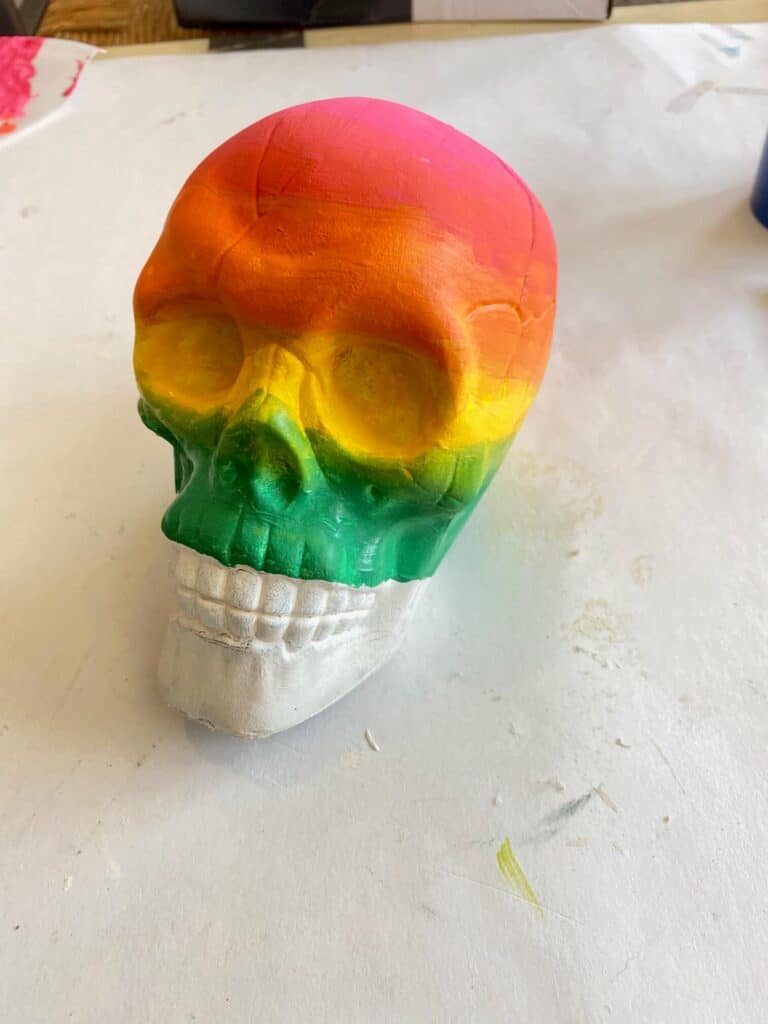 Pink, orange. yellow, green painted Dollar tree skull, painted with the ombre effect to blend each color into the next.