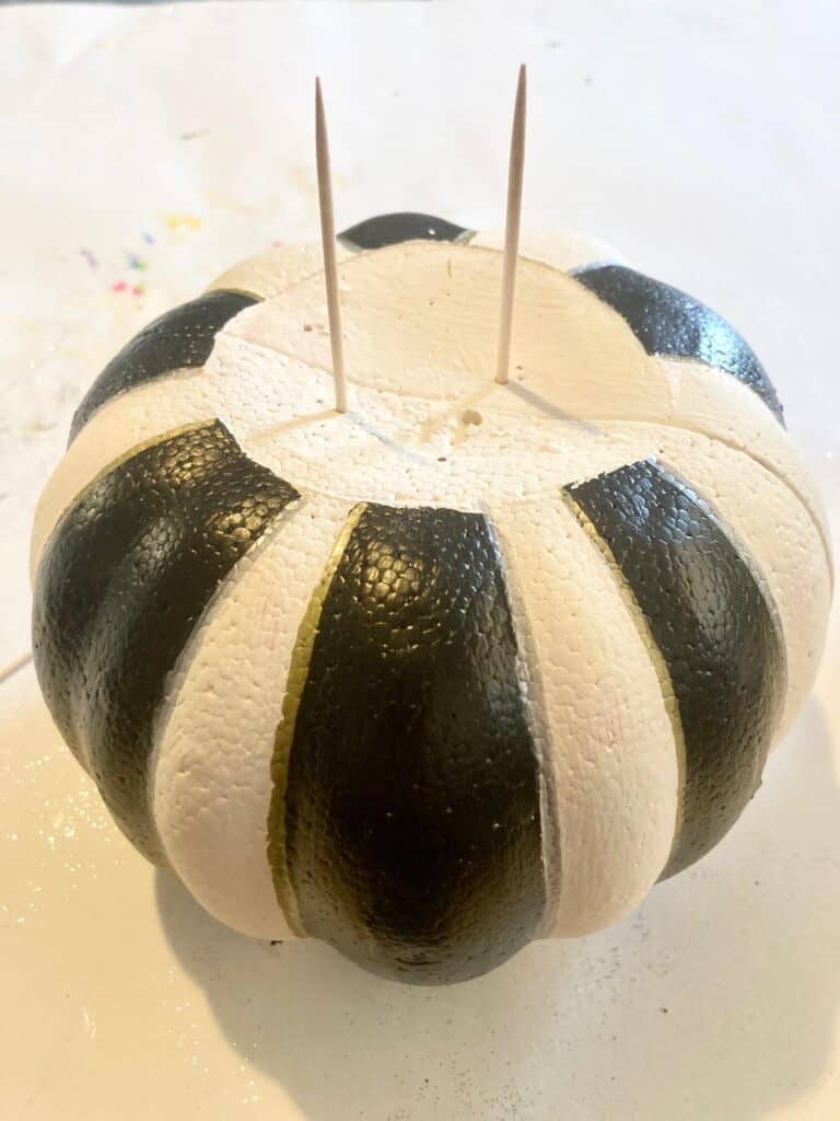 Insert 2 toothpicks in the top of the DIY white and black stripe painted dollar tree foam pumpkin so that you can stack them to make a topiary.