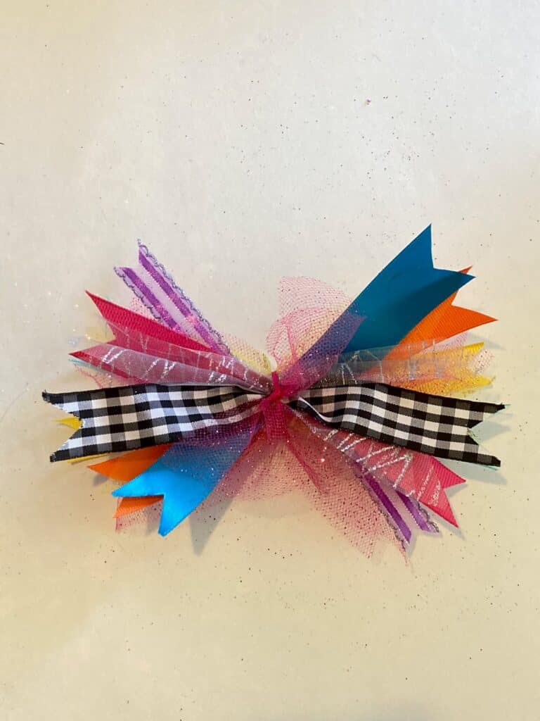 Make a scrappy rainbow bow with 6 inch strips or ribbon and tulle. Add a black and white buffalo check ribbon and tie in the center.