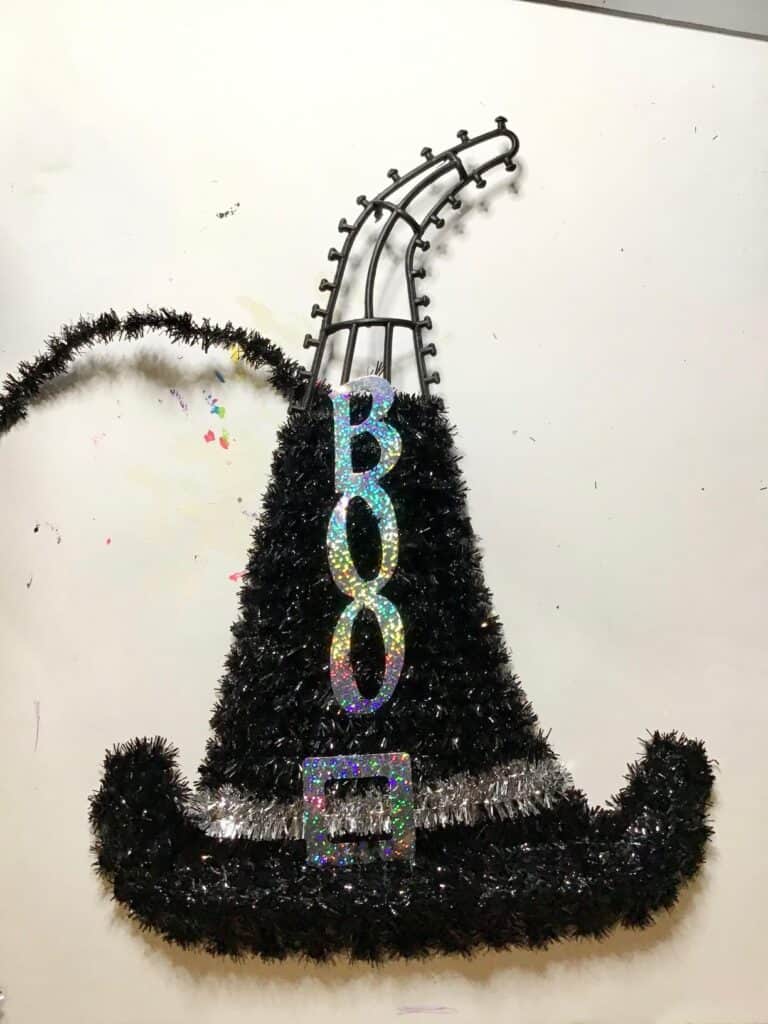 Remove the black tinsel and the 'Boo' from the Black Witch Hat decoration, leaving only the plastic wreath frame.