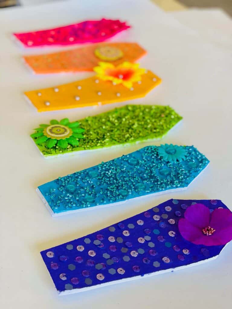 Blinged out rainbow coffins with multicolored glitter and sequins. Fun DIY Halloween party decorations.