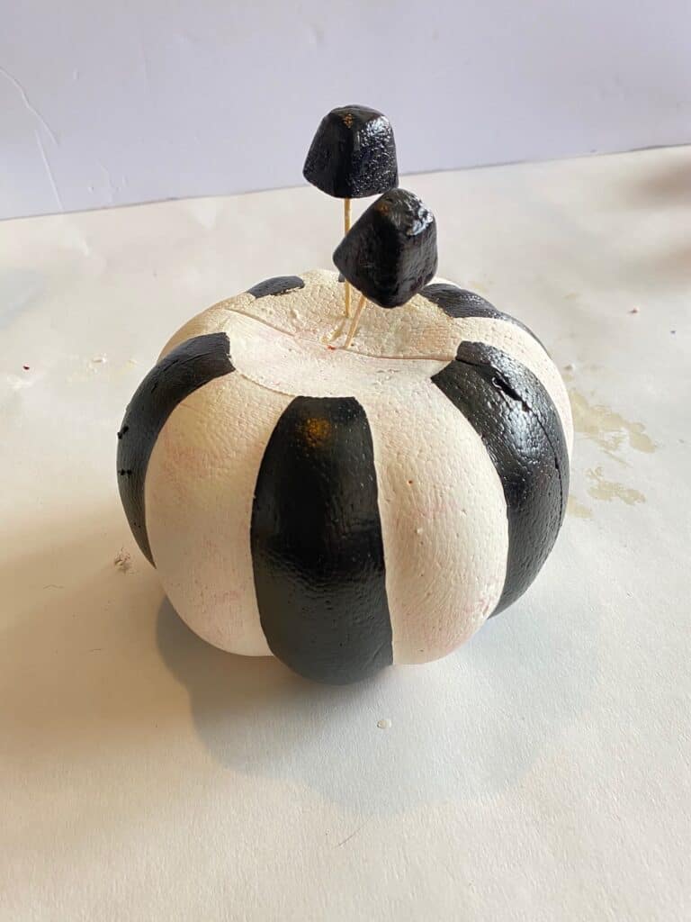 DIY Dollar tree orange carveable foam pumpkin painted all white with chalk paint and black stripes.