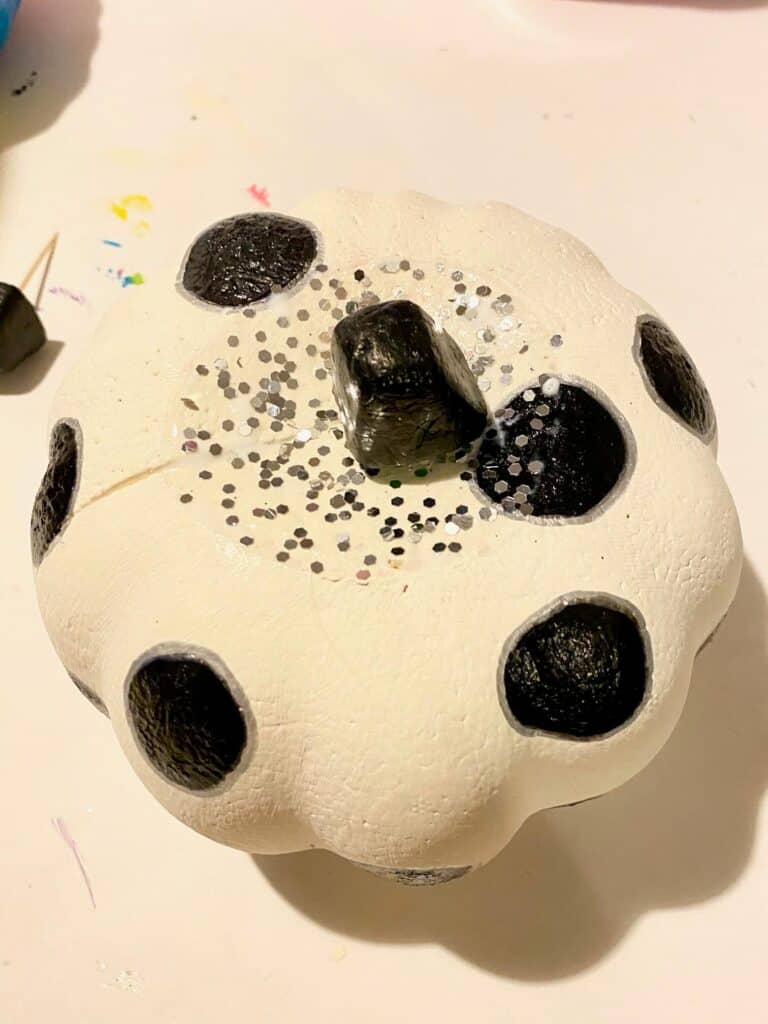 Paint the stem black and Add mod podge and silver glitter to the top of the DIY white and black polka dot painted dollar tree foam pumpkin.