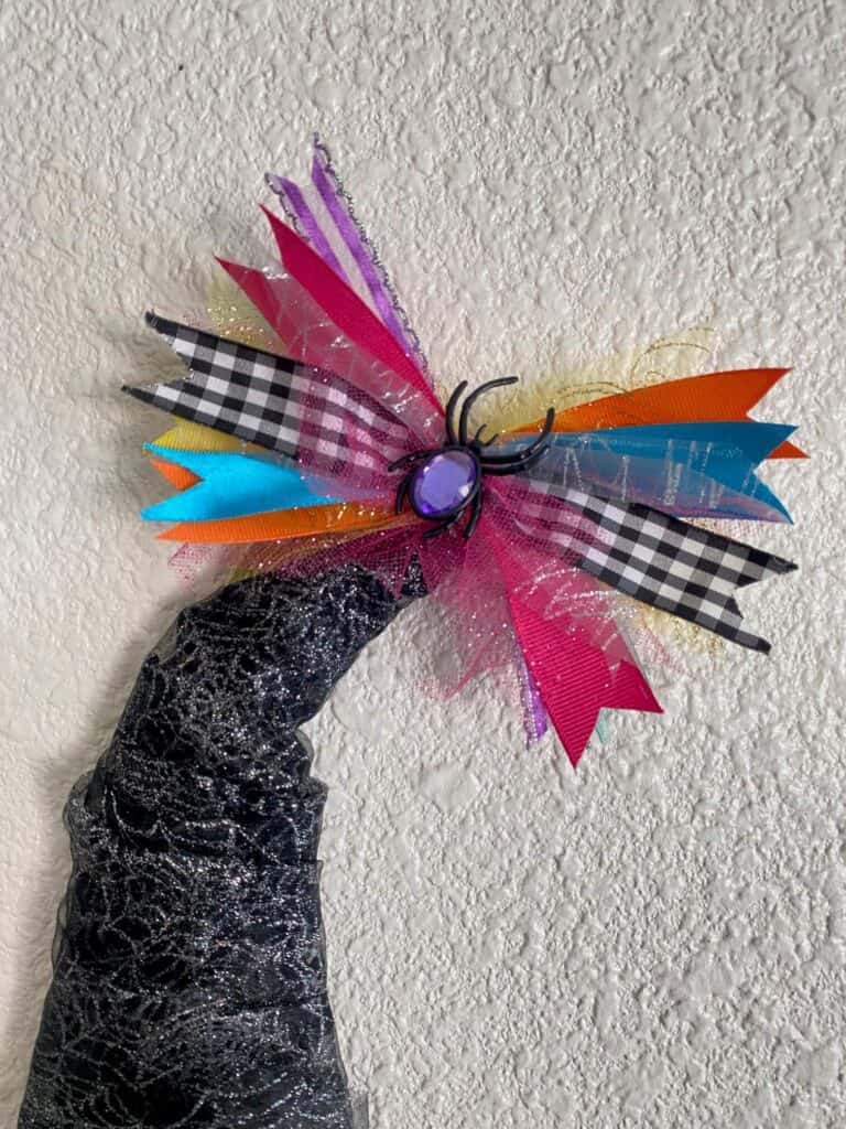 Glue the rainBow to the tip top of the Deco Mesh Witch Hat Wreath, and glue a fake jewel spider to the center.