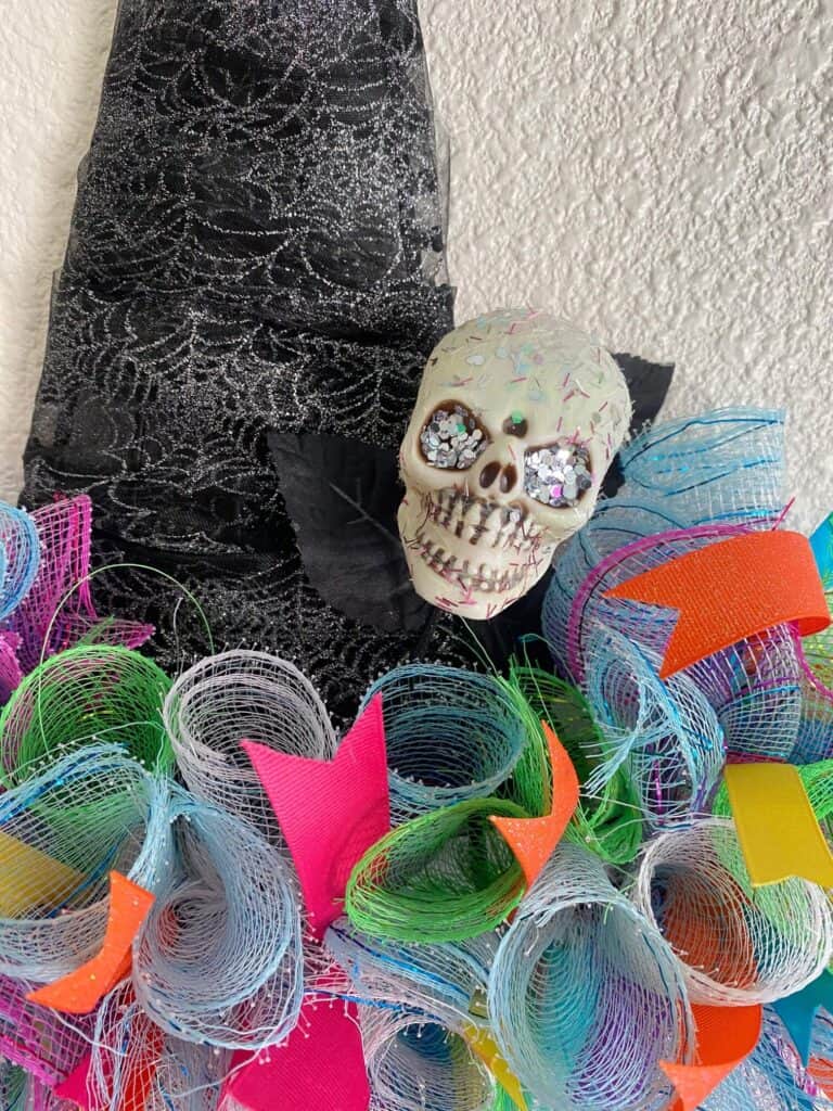 Cover the skull head with a generous layer of Mod Podge and sprinkle as much glitter as you'd like to jazz it up. Stick the glitter skull pick into the mesh part of the wreath, 