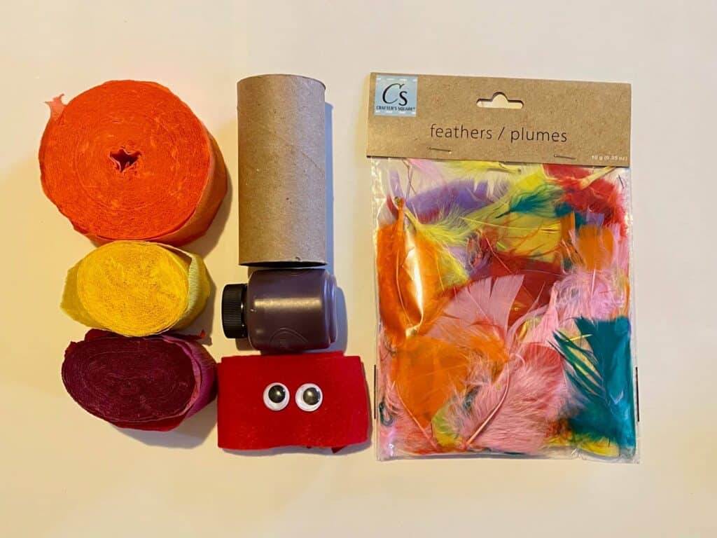 Supplies needed to make a Toilet paper roll turkey windsock. Yellow orange and red crepe paper, toilet paper roll, felt, googly eyes, and feathers.