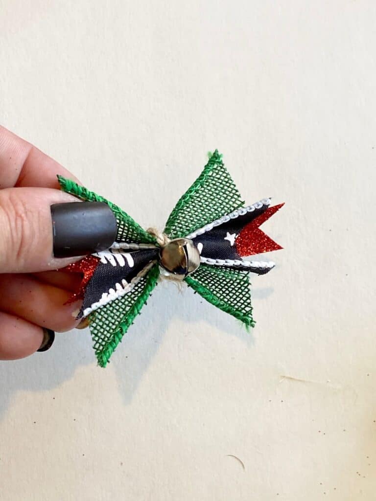 Scrap ribbon bow, green burlap, red sparkly, and grey with white christmas tree and a mini silver bell.