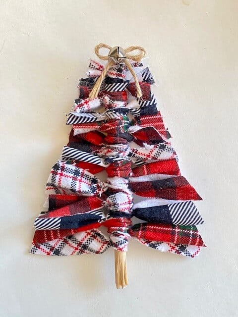 Scrap fabric christmas tree using all leftover craft supplies with a twine bow and a mini silver bell. Buffalo check, black and white, and red green white plaid fabric.