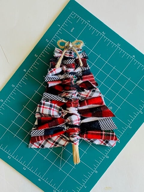 Scrap fabric christmas tree on a green fabric cutting mat. Buffalo check, black and white, and red green white plaid fabric.