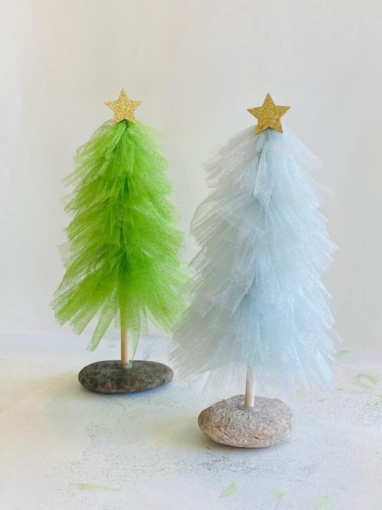 Dollar Tree DIY Glitter Tulle Christmas Tree decorations with a wooden dowel and a natural rock base.