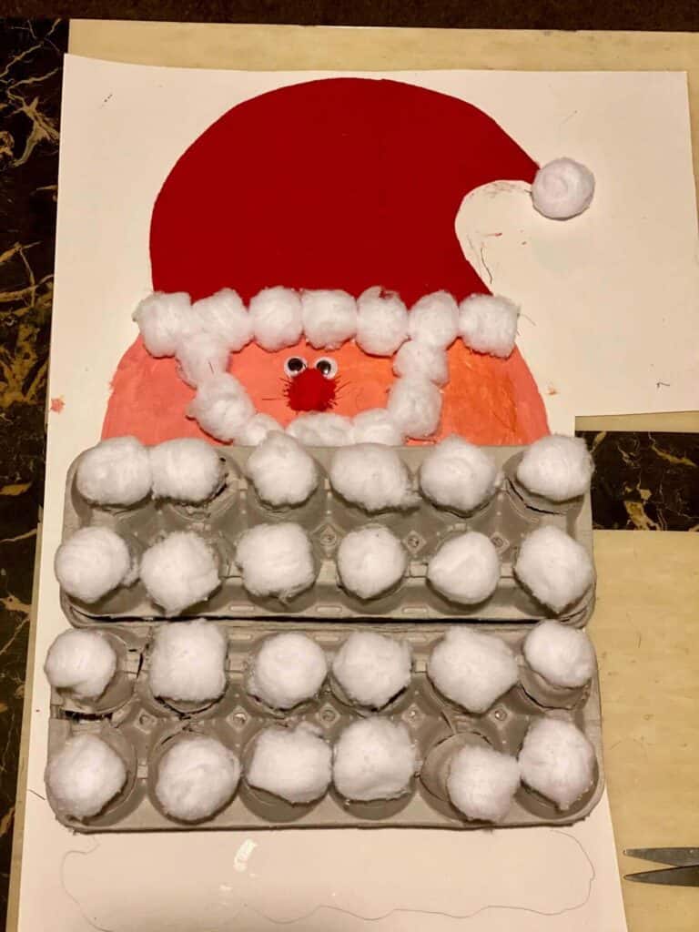 Santa face and hat advent calendar with an egg carton cotton ball beard, glued to white foam board.