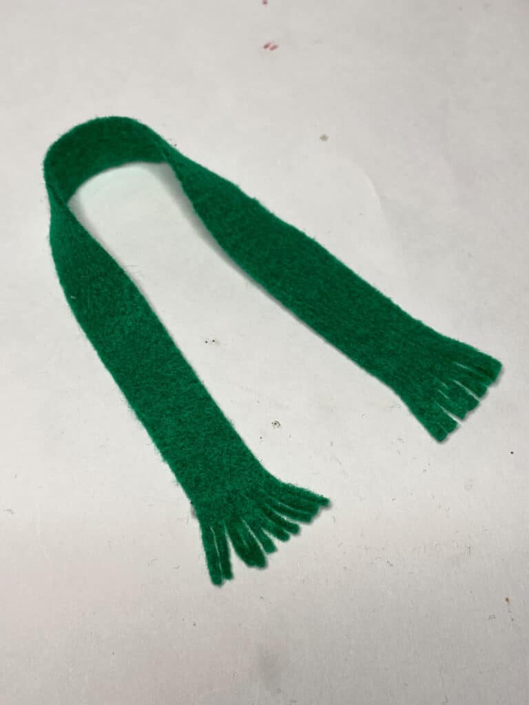 1 inch thick strip of green felt with the ends fringe cut to look like a scarf.