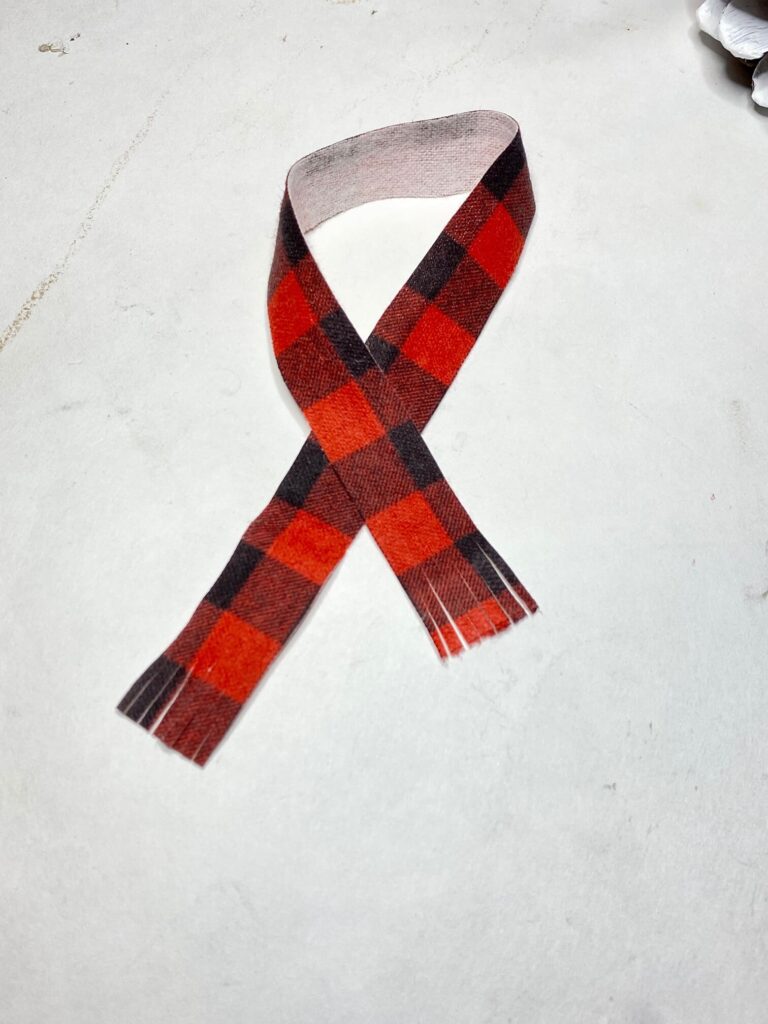 Red and black buffalo check fabric strip with fringed ends to make a scarf.