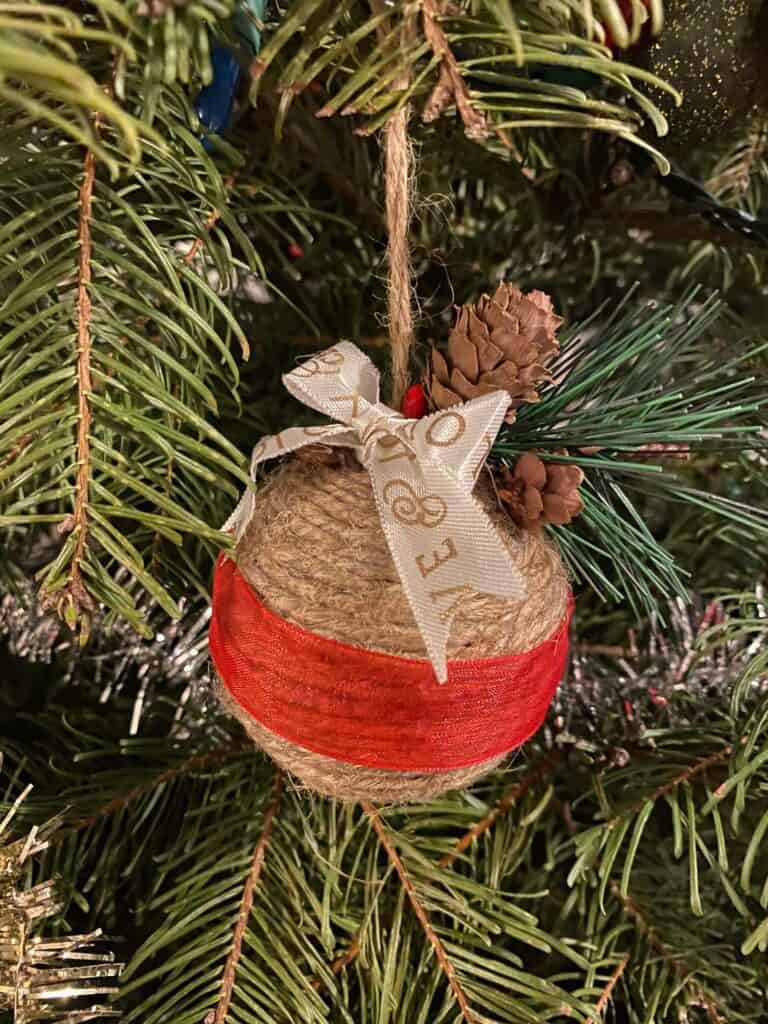 Handmade DIY Twine Wrapped Ball Christmas Tree ornament made with leftover supplies from your craft stash hanging on a christmas tree.