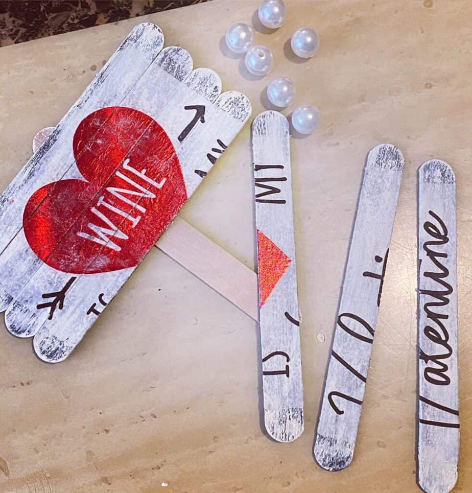 Wine is my valentine napkin mod podged onto painted popsicle sticks, with the sticks broken into separate "planks" and pearl beads next to it.