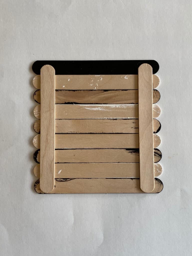 Back of the black and white popsicle sticks, showing the 2 sticks glued vertically to hold it together.