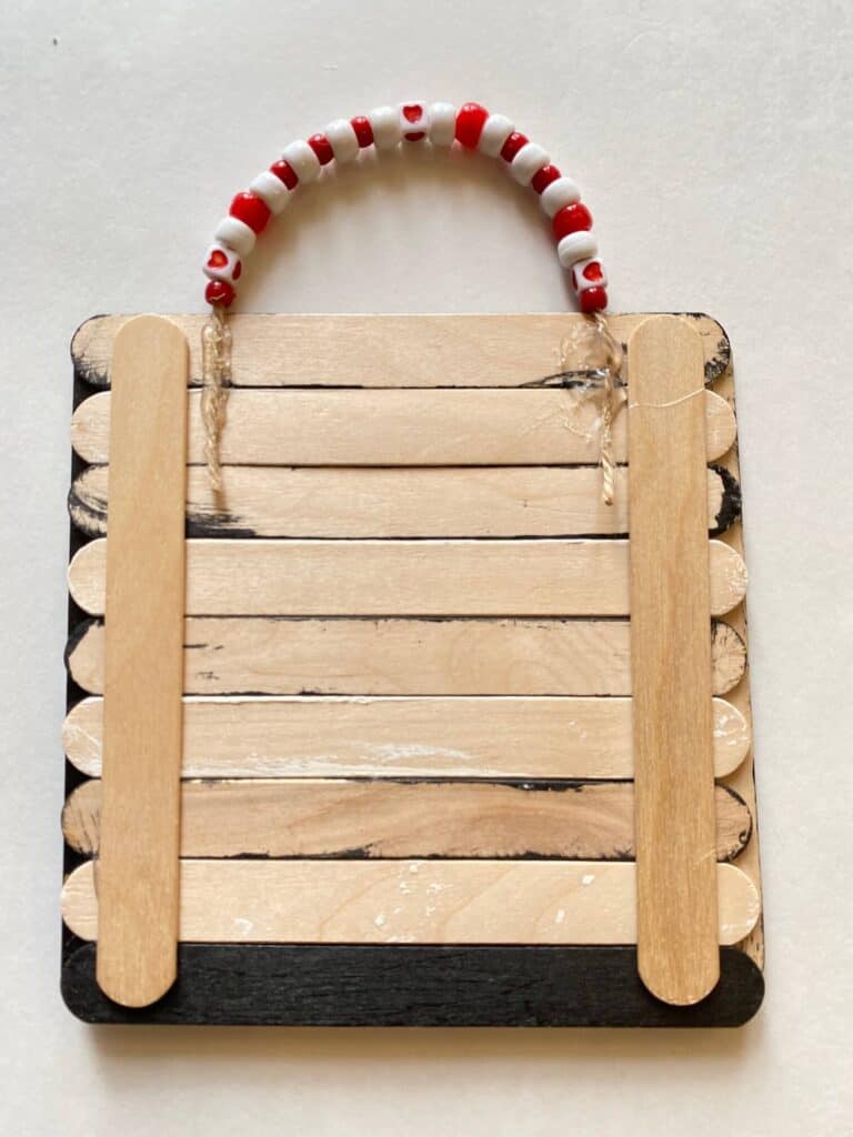 Back of the black and white popsicle sticks, showing the bead hanger glued to the back to hang the valentines sign.