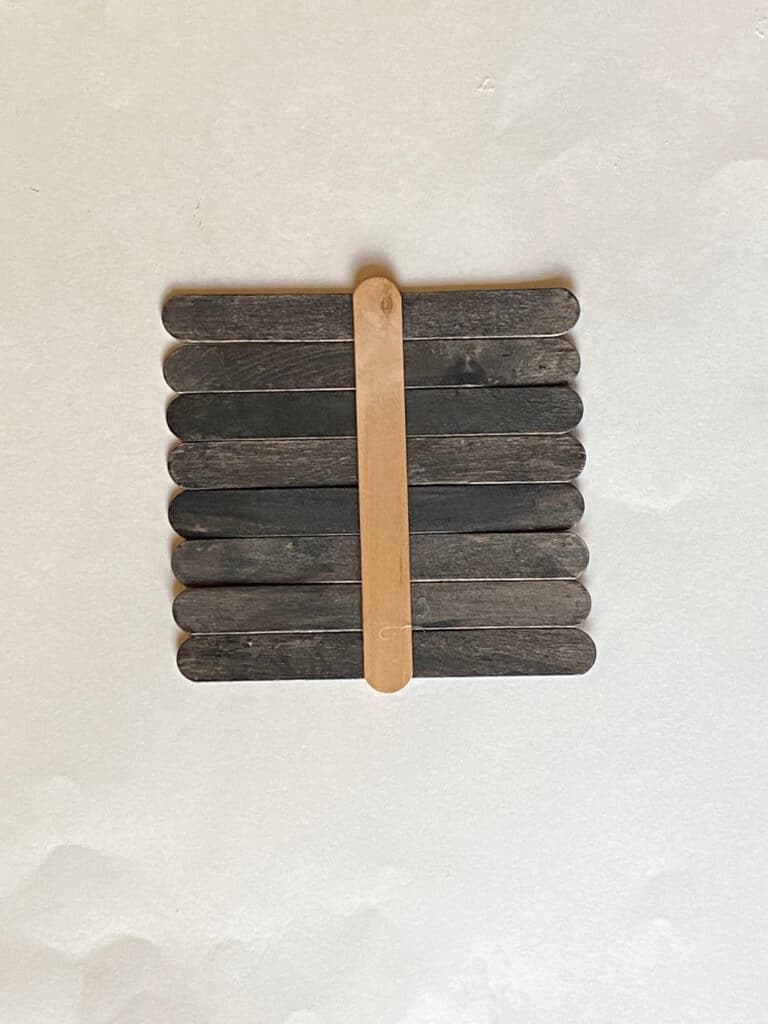 The back of the painted popsicle sticks held together with a popsicle stick glued across them.