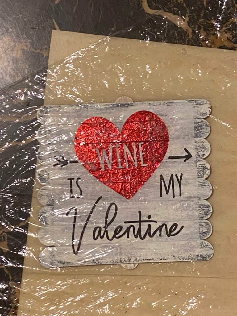 Valentine napkin mod podged onto the painted popsicle sticks with saran wrap over the top to smooth out the bubbles.