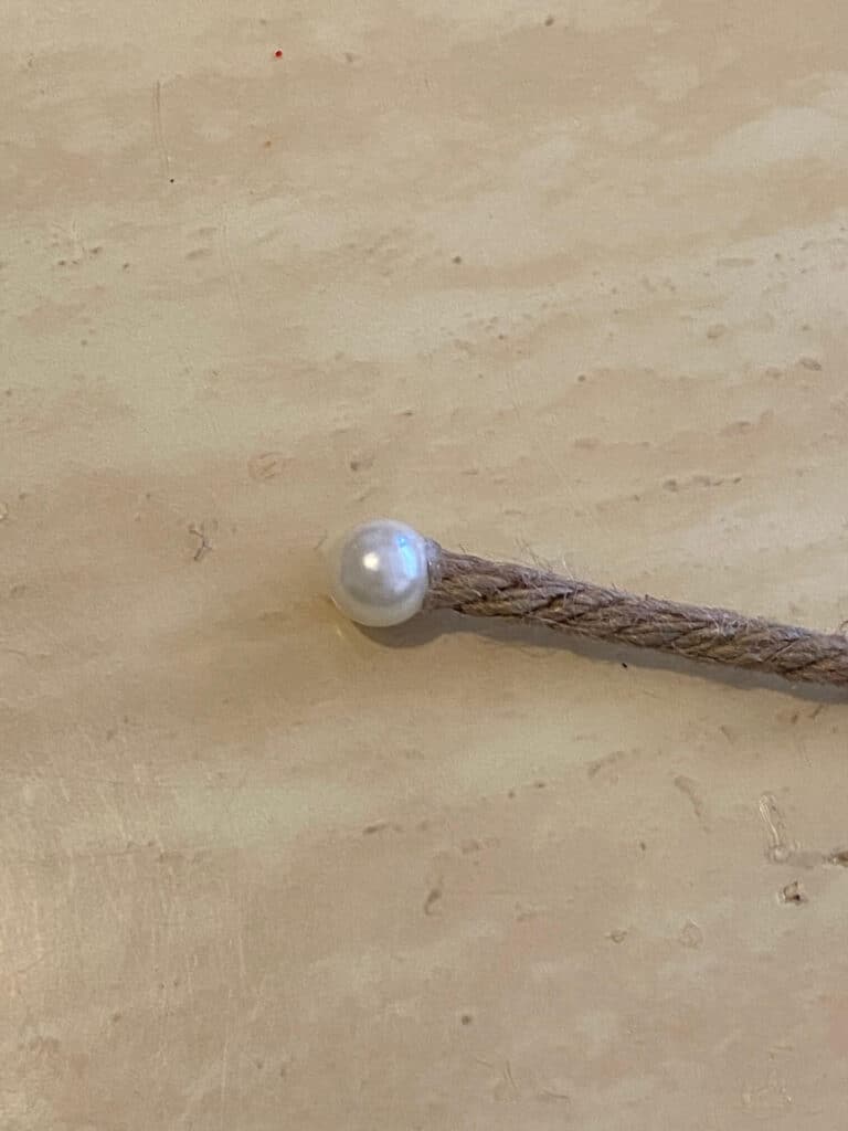A pearl bead glued to the end of a piece of nautical rope.