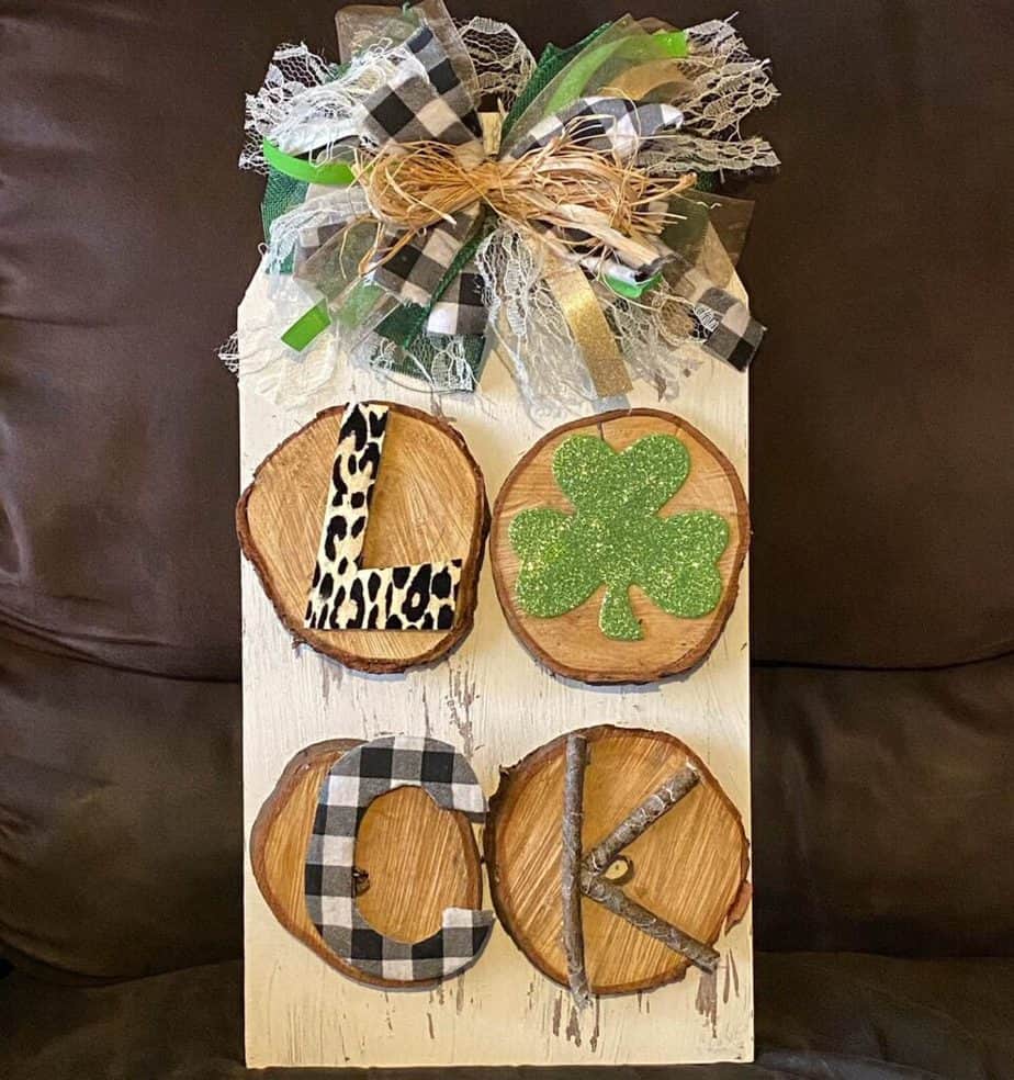 DIY Rustic and Shabby Chic St. Patrick's Day Door hanger with Leopard print and buffalo check LUCK on wooden rounds on the back of a Dollar Tree sign.