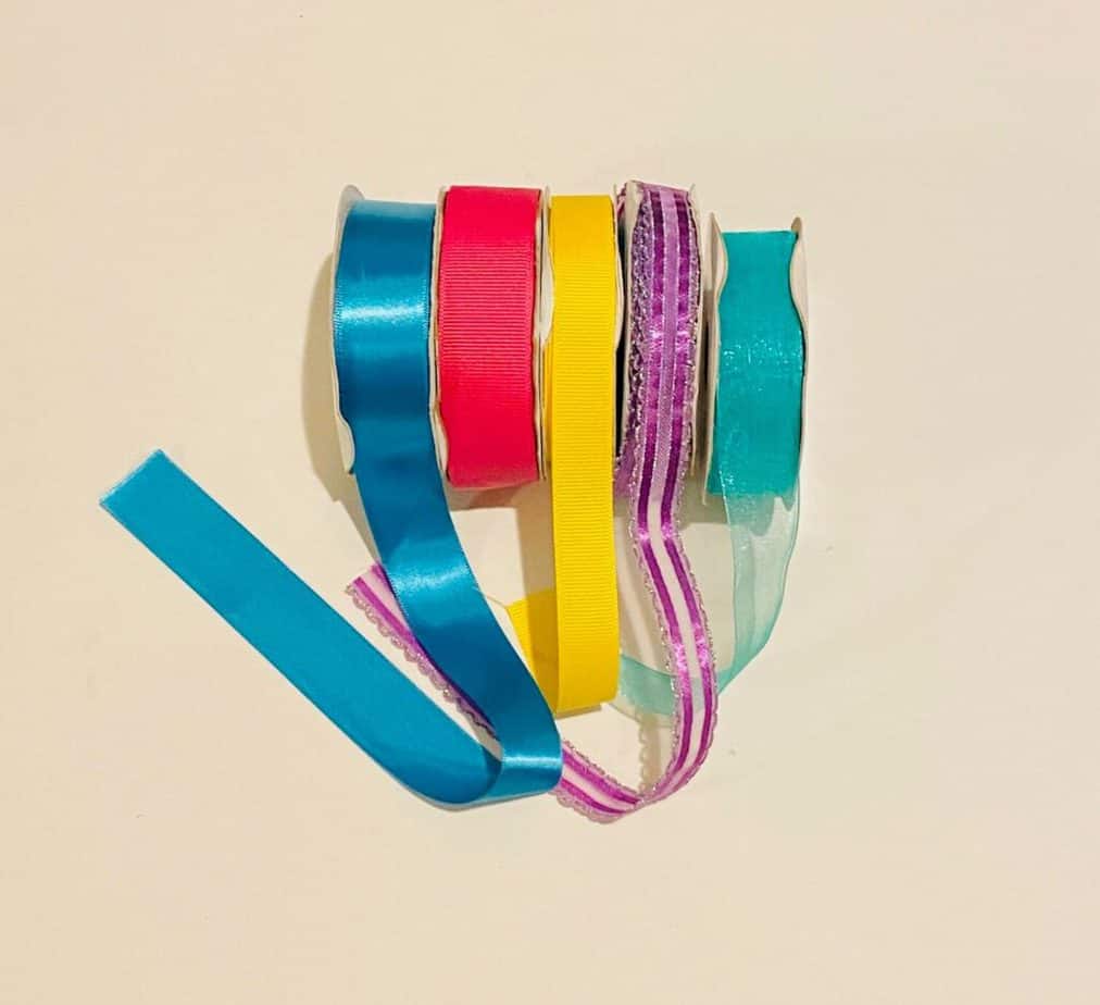 5 colored spools of ribbon, blue, pink, yellow, purple, teal.