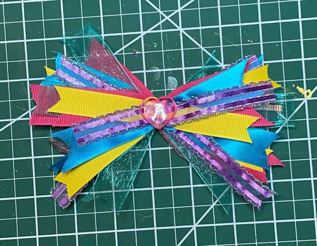 Colorful scrap ribbon bow with a pink heart embellishment to add as a decoration on top of the Dollar Tree foam wreath.