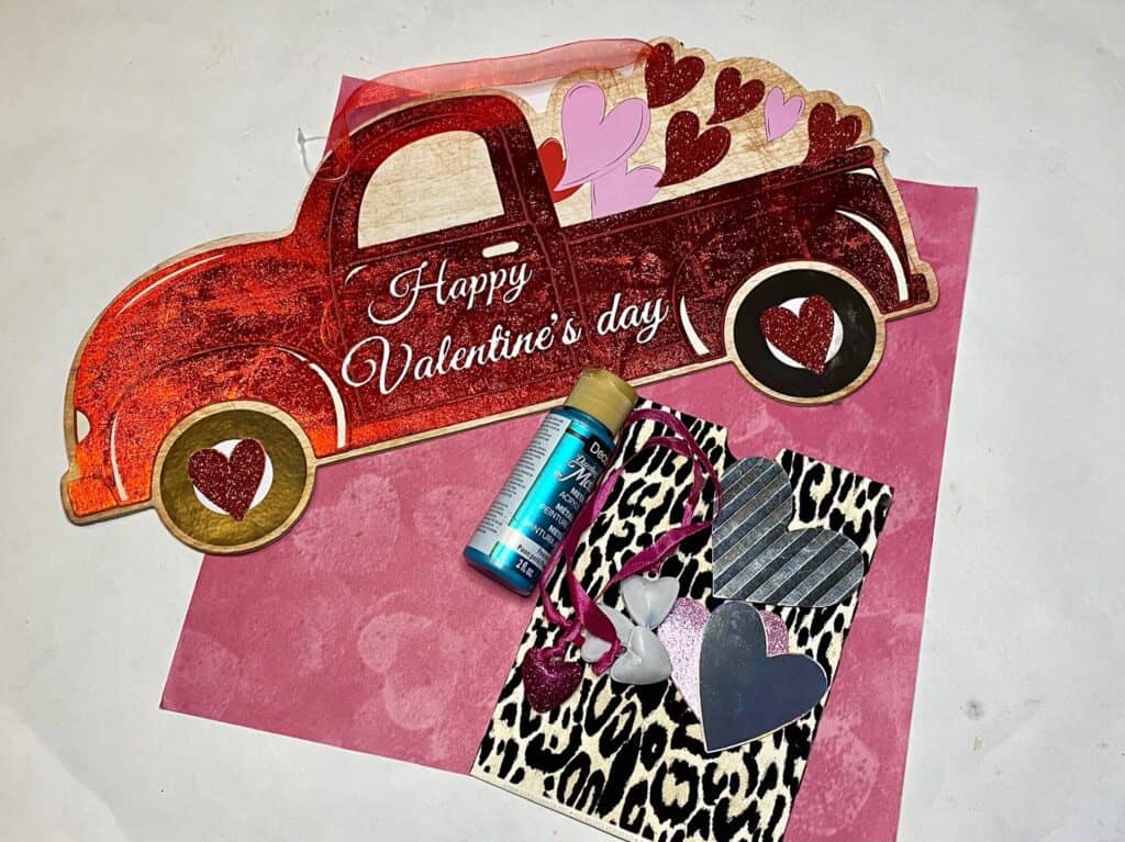 Supplies needed for the Valentines red truck makeover with leopard paper, pink heart scrapbook paper, metal hearts, metallic teal paint .