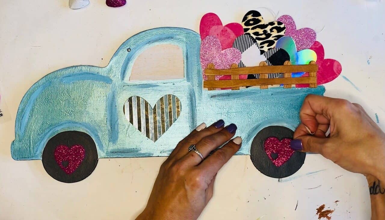 Put the finishing touches on the Dollar tree Valentines red Truck by adding pink glitter hearts to the center of the tires.