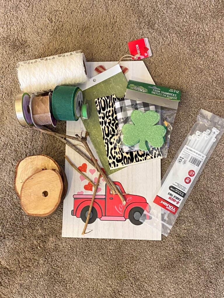 All of the supplies needed to make a DIY St. Patrick's Day door hanger with the word "LUCK" on wooden rounds in leopard and buffalo check with a shamrock.