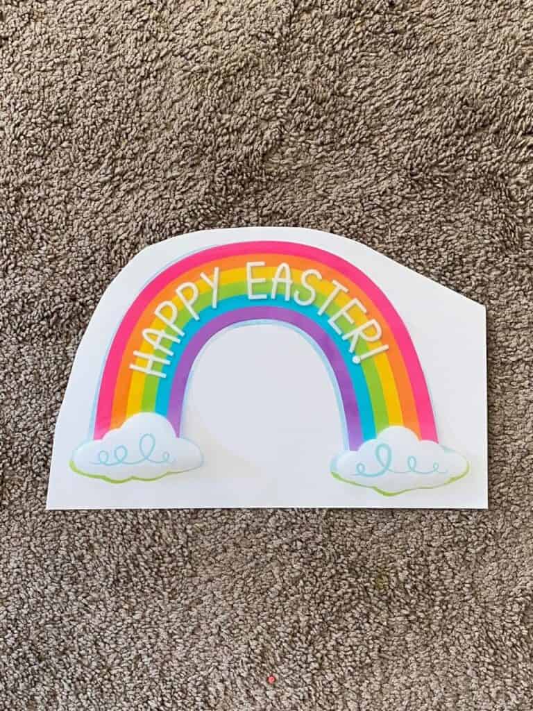 Rainbow Happy Easter window cling glued to a white poster board.