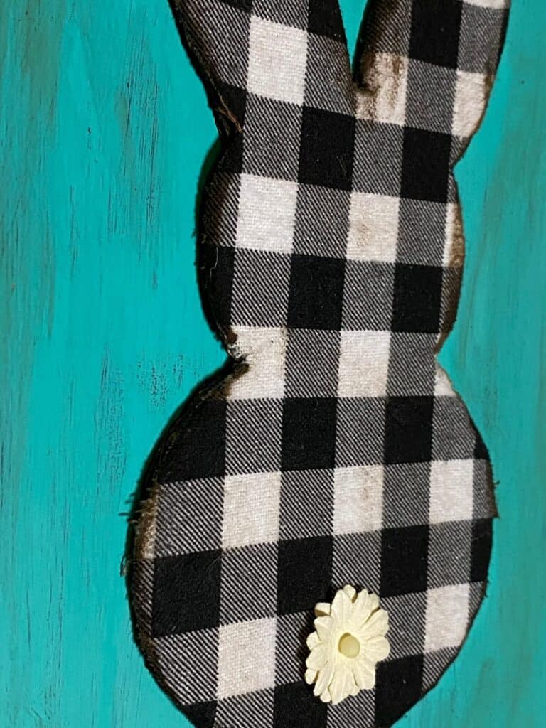 Close up of the Buffalo check Easter bunny with antiqued distressed edges stained brown. on a teal painted wooden sign.
