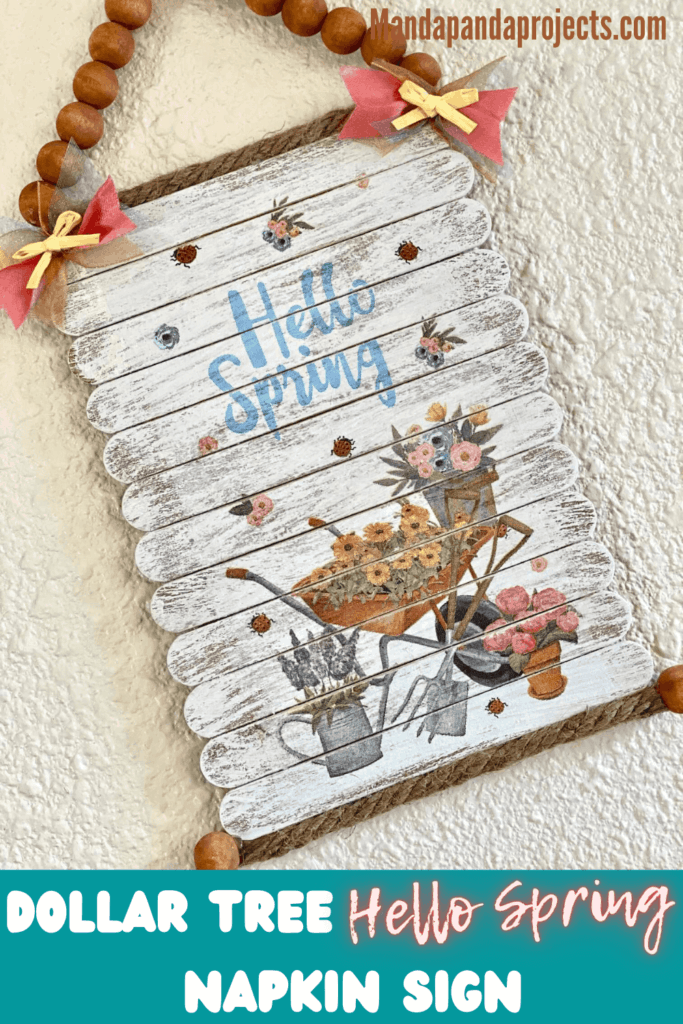 DIY Dollar Tree "Hello Spring" napkin sign made with popsicle stick planks for easy spring crafts and decor. Napkin has a wheelbarrow filled with sunflowers and garden tools.