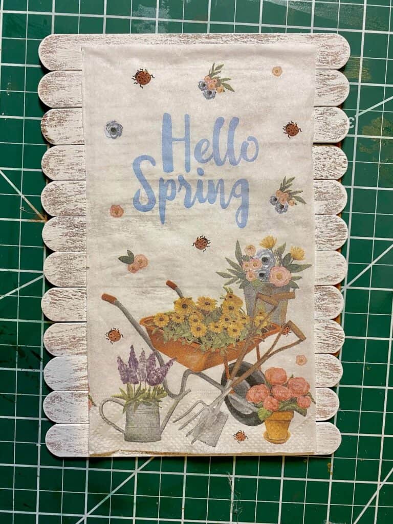 Mod Podge the Dollar Tree "Hello Spring" napkin to the top of the white painted popsicle sticks.
