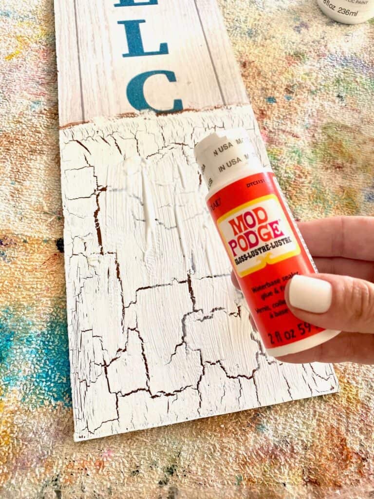 Apply a generous layer of Mod Podge to the surface of the crackle paint, and lay the One in a Melon napkin on top.