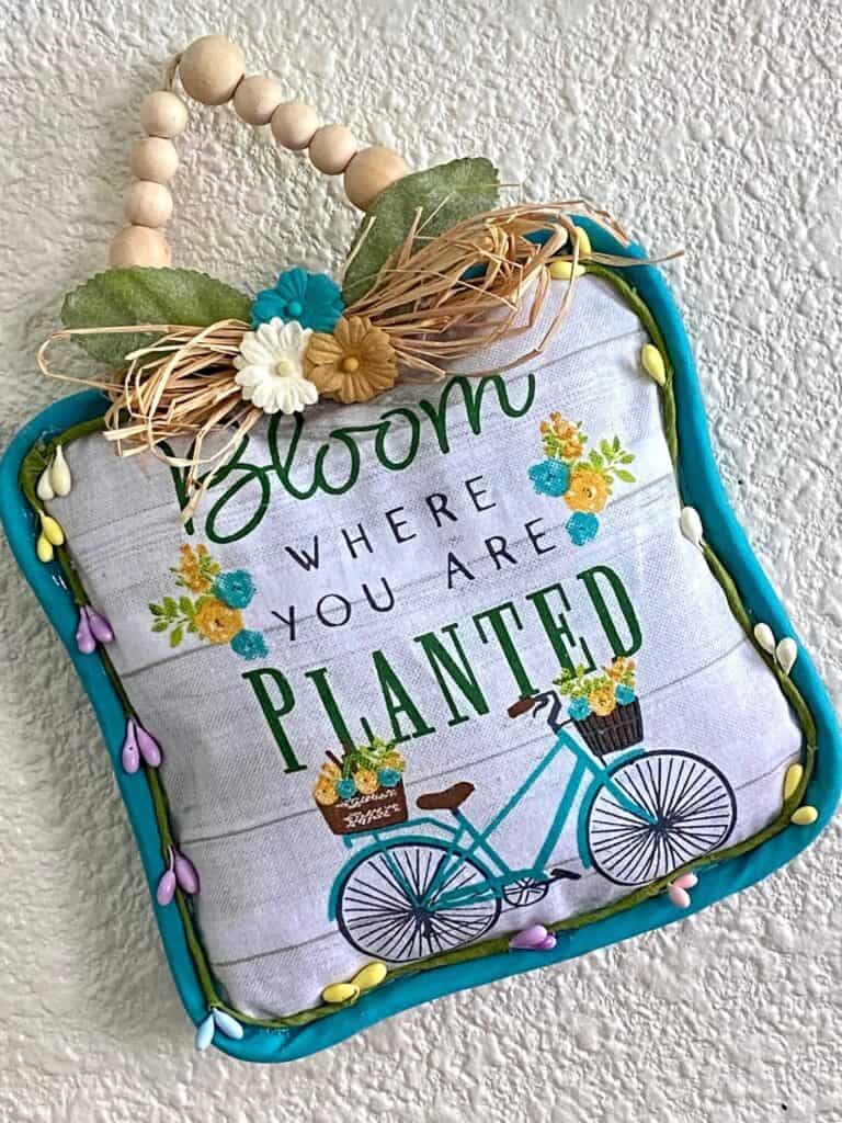 Dollar Tree 'Bloom Where you Are Planted' Pot Holder DIY Doorknob Hanger with a raffia bow and wood bead hanger.