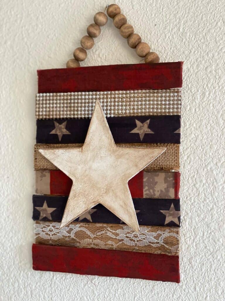 Rustic distressed star on a patriotic color background with burlap. lace, and pearl.
