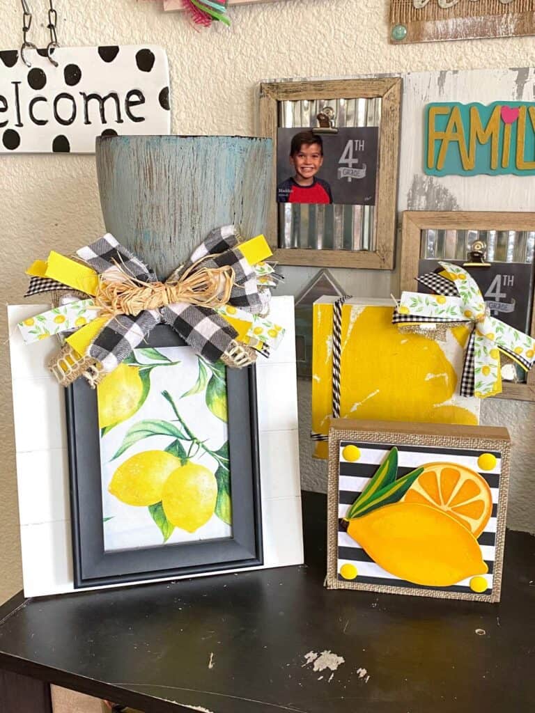 Several yellow and black and white lemon crafts and decor sitting on a bookshelf decorated in lemons for summer.