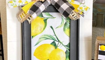 DIY summer Lemon Layered frame with a plain black dollar tree frame, Lemon fabric inside, layered on top of a white pallet board with a messy scrap ribbon bow on top.