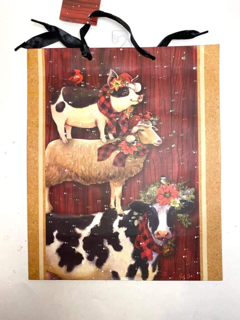 Dollar Tree Farmhouse Christmas Gift Bag with a cow, pig, and sheep standing on each others back. 
